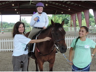 It's all smiles for SI Club Member, Susan Heimber, and volunteer Alina as rider, Katie R. and horse, Devon show off their ribbon.